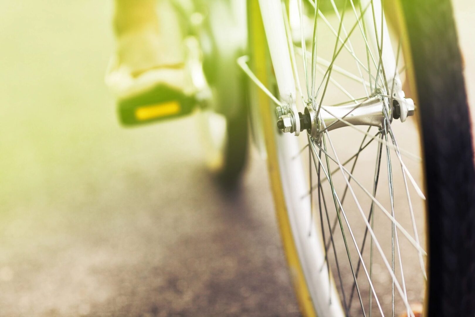Close-up of a bicycle wheel on a sunny road.