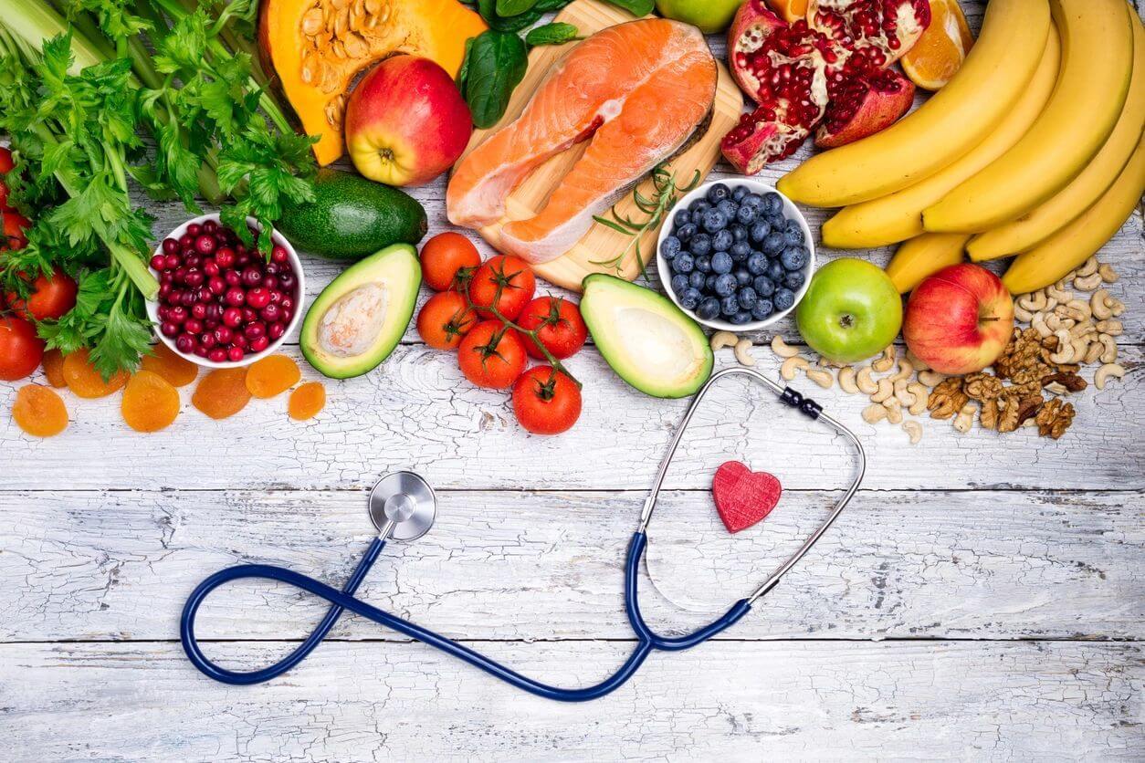 Healthy foods and a stethoscope shaped like a heart on a wooden table.