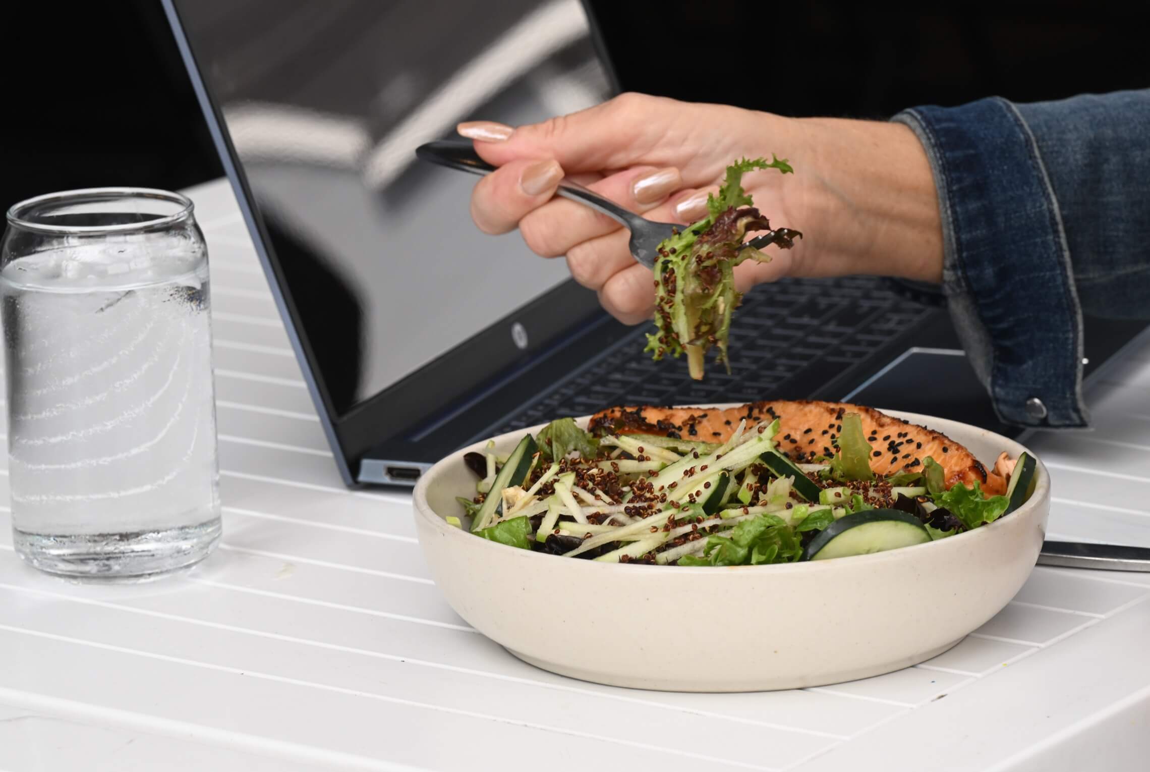 Person eating a fresh salad with chopsticks at a table.