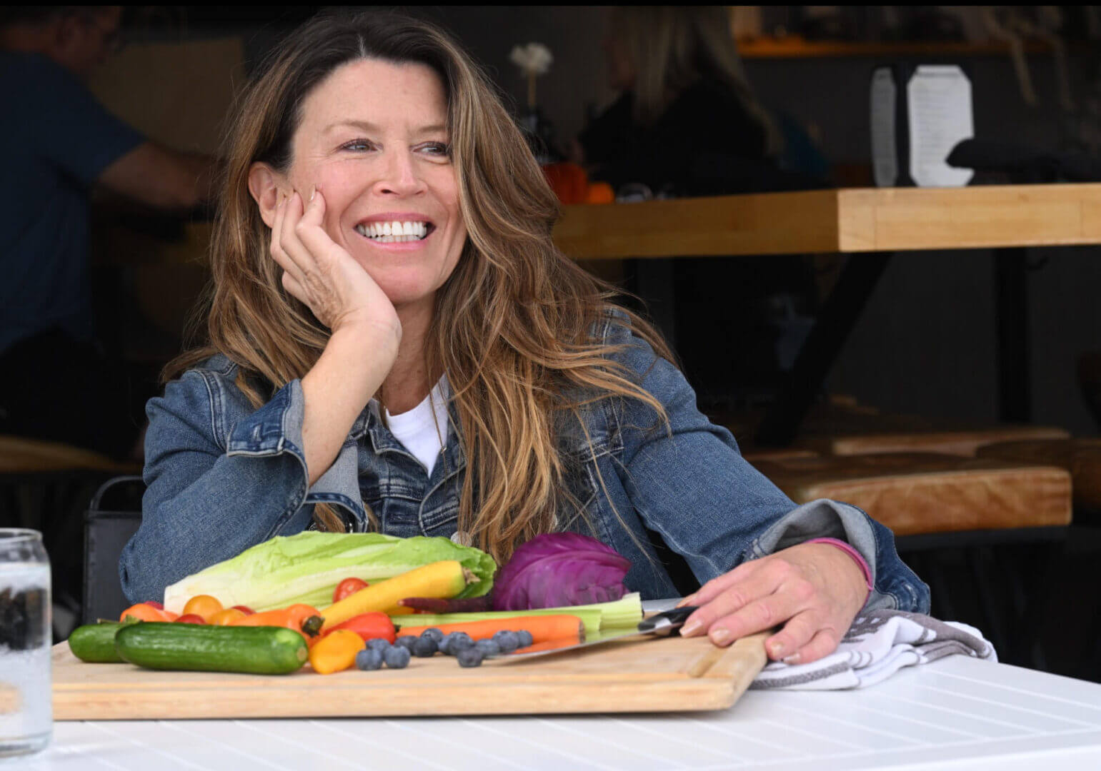 A smiling woman preparing fresh vegetables at a table.